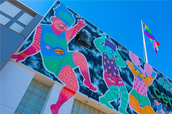 Front view of a building with colorful mural and a flag pole on top.