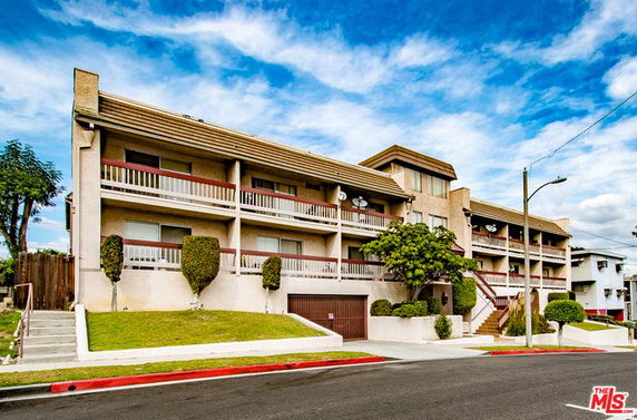 Front view of a multi-story building with balconies and a garage.