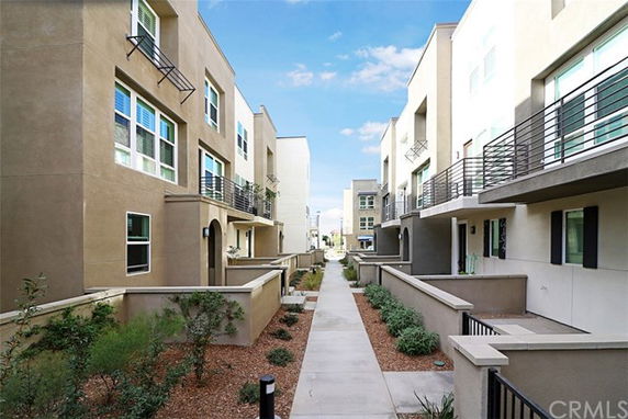 View of modern multi-story residential buildings with balconies and landscaped walkway.