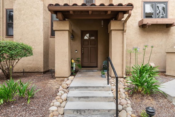 Front view of a house with a covered entrance and steps leading up.