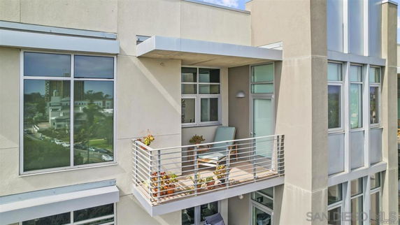 View of a modern building exterior with large windows and a small balcony.