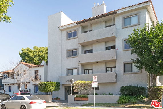 Front view of a multi-story residential building with balconies and a flat roof.