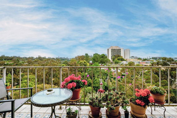 View from a balcony overlooking trees and buildings in the distance.