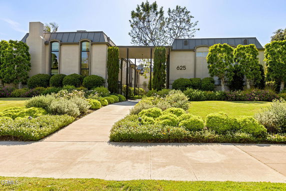 Front view of a modern multi-story building with large windows and a landscaped garden.