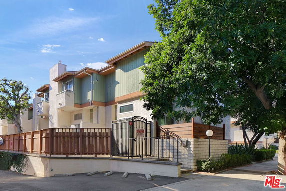 Front view of a multi-story residential building with wooden fencing.