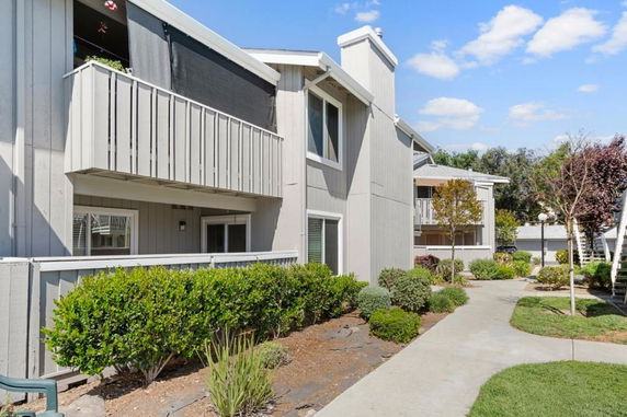 Front view of a two-story residential building with balconies and a well-maintained garden.