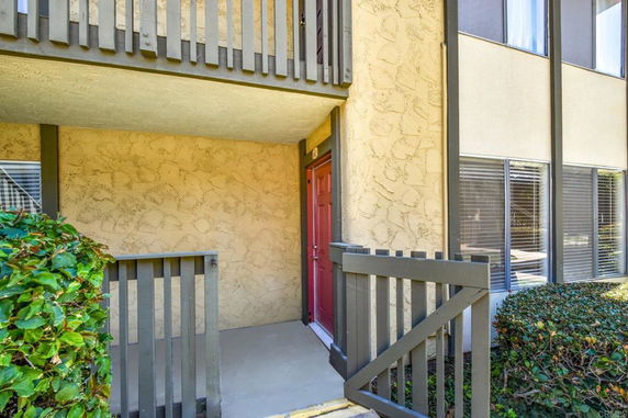 Front view of a multi-story building entrance with a small gated porch and red door.