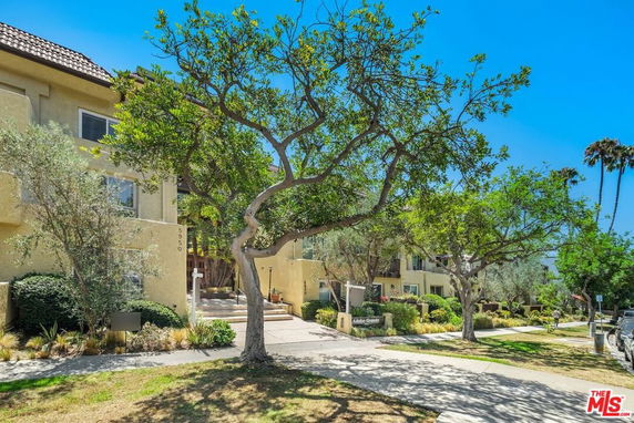 Front view of a multi-story residential building with trees and landscaping.