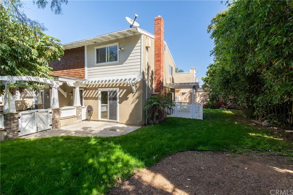 Rear view of a two-story house with a patio and pergola.