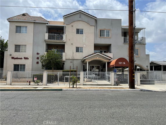 Front view of a multi-story building with balconies and a gated entrance.