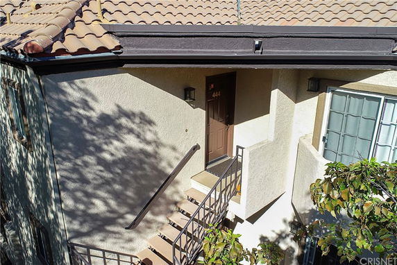 Front view of a house with a tiled roof and staircase leading to a door.