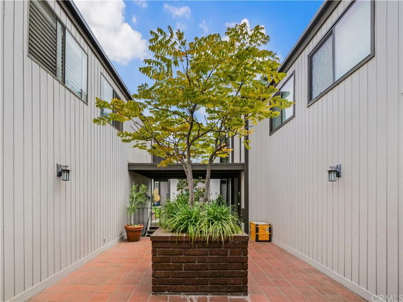 Front view of a modern house with siding and a central planted tree in the entrance area.