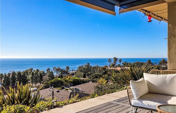 Panoramic ocean view from a terrace with outdoor seating.