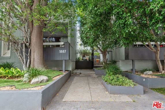 Front view of a building with a gated entrance and trees.