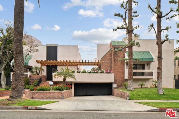 Front view of a contemporary two-story building with a garage and green awnings.