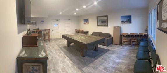 Room with tables, chairs, and a covered pool table in a clubhouse setting.