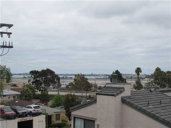 View from building showing rooftops and surrounding areas with distant water and trees.