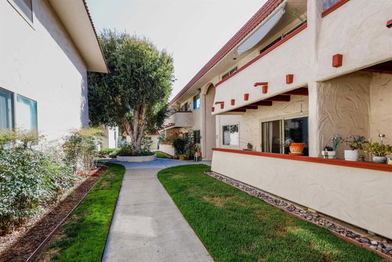Pathway between two residential buildings with textured walls and decorated balconies.