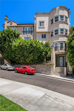 Front view of a multi-story residential building with bay windows and a gated entrance.