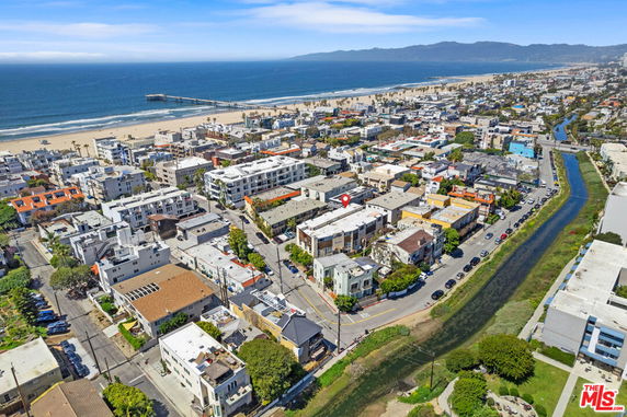 Aerial view of a coastal neighborhood with buildings, beach, and ocean.