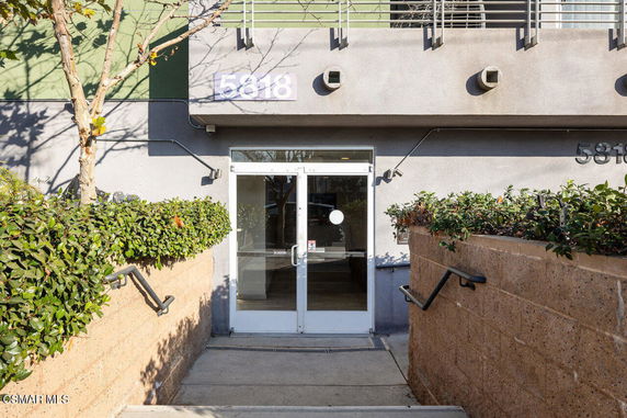 Front view of a building entrance with double glass doors and the number 5818 displayed above.