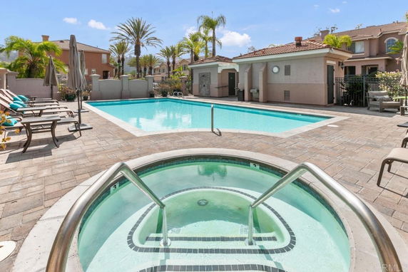 Outdoor swimming pool with lounge chairs and umbrellas nearby.