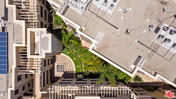 Aerial view of building rooftops with solar panels and air conditioning units.