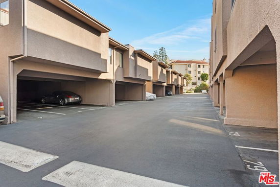 Outdoor parking area beneath residential buildings with parked cars.