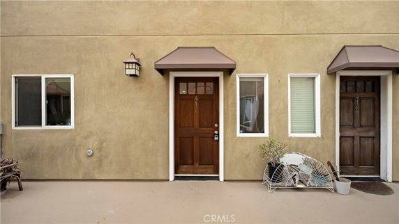 Front view of a building entrance with two wooden doors and small windows.