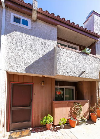 Front view of a two-story building with stucco finish and a small balcony.