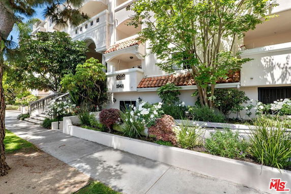 Front view of a multi-story building with a staircase and landscaped garden.
