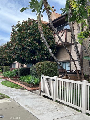 Front view of a two-story house with a hedge and trees.