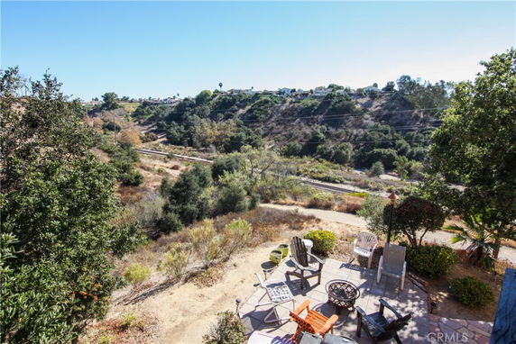 Panoramic view of a hilly landscape with patio furniture and vegetation in the foreground.