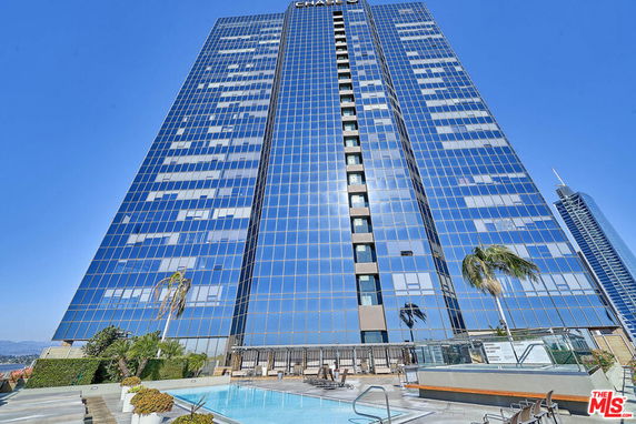 Front view of a tall building with reflective glass facade and outdoor swimming pool area.