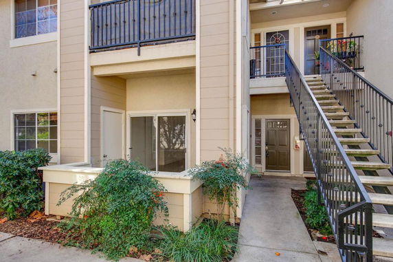 Front view of a multi-story residential building with an external staircase and balconies.