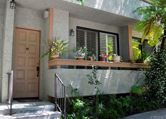 Front view of a house entrance with a small porch and potted plants.