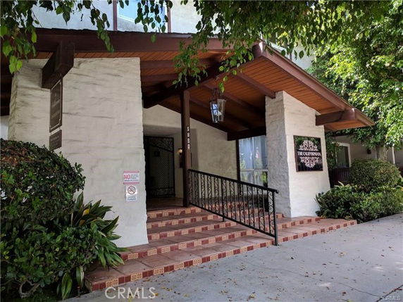 Front view of a building entrance with tiled steps and a wooden awning.