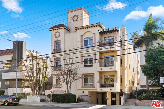 Front view of a multi-story residential building with balconies and decorative elements.