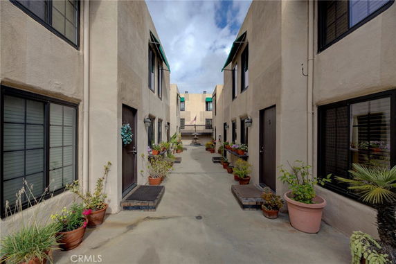 View of an apartment building entrance with potted plants along the pathway.