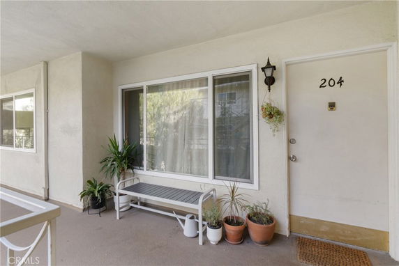 Front view of an apartment entrance with a bench and potted plants.