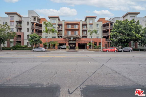 Front view of a multi-story residential building with balconies and a central entrance.