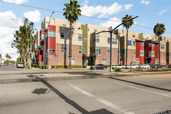 Street view of a modern multi-story apartment building with geometric design and colorful facade.
