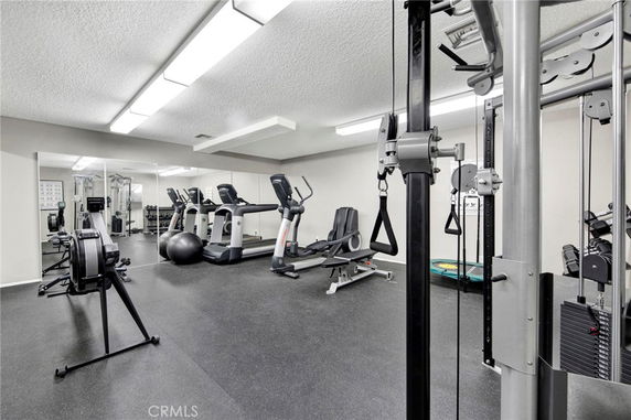 Fitness room with various gym equipment including treadmills and weight machines.