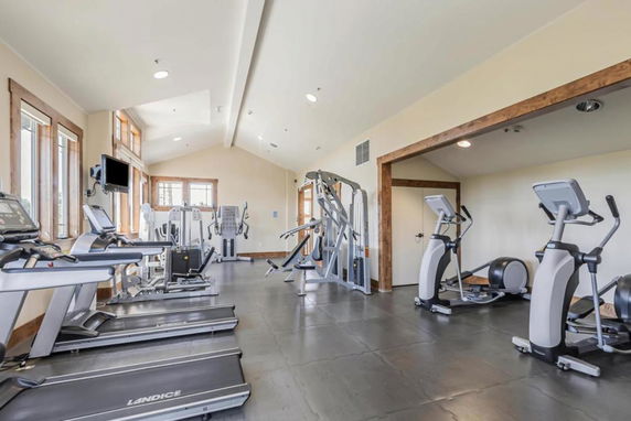 Interior view of a room with gym equipment including treadmills, exercise bikes, and weight machines.