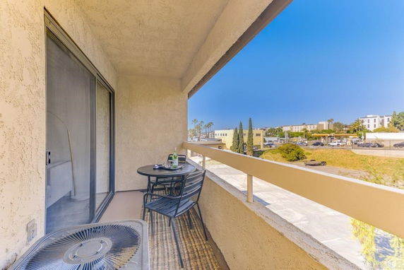 Balcony view with a small table and chairs overlooking suburban surroundings.