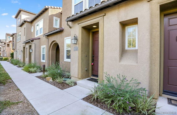 Front view of a multi-story townhouse with stucco finish and decorative arches.