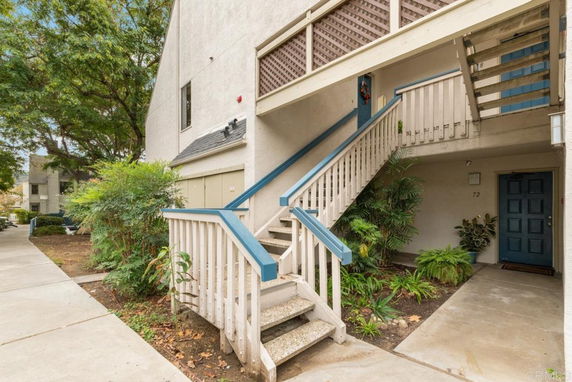 Front view of a multi-level building with stairs leading to a blue door.
