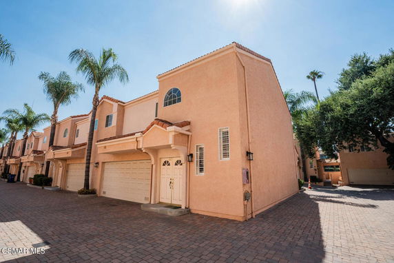Front view of a two-story townhouse with garage and decorative roof shingles.
