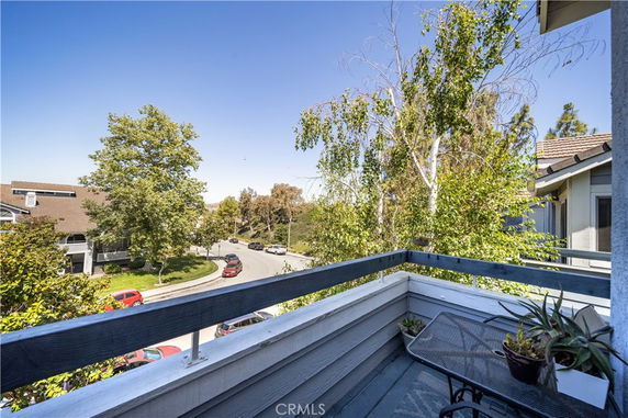 View from a balcony overlooking a residential street with trees and houses.