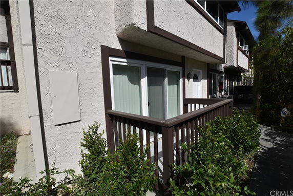 Front view of a multi-story building with a small balcony and sliding door.